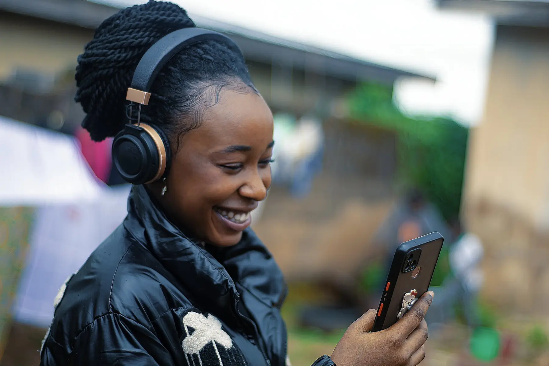 Young woman with headphones smiling at her phone