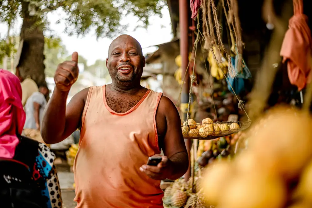 Smiling trader giving a thumbs up at his market stall